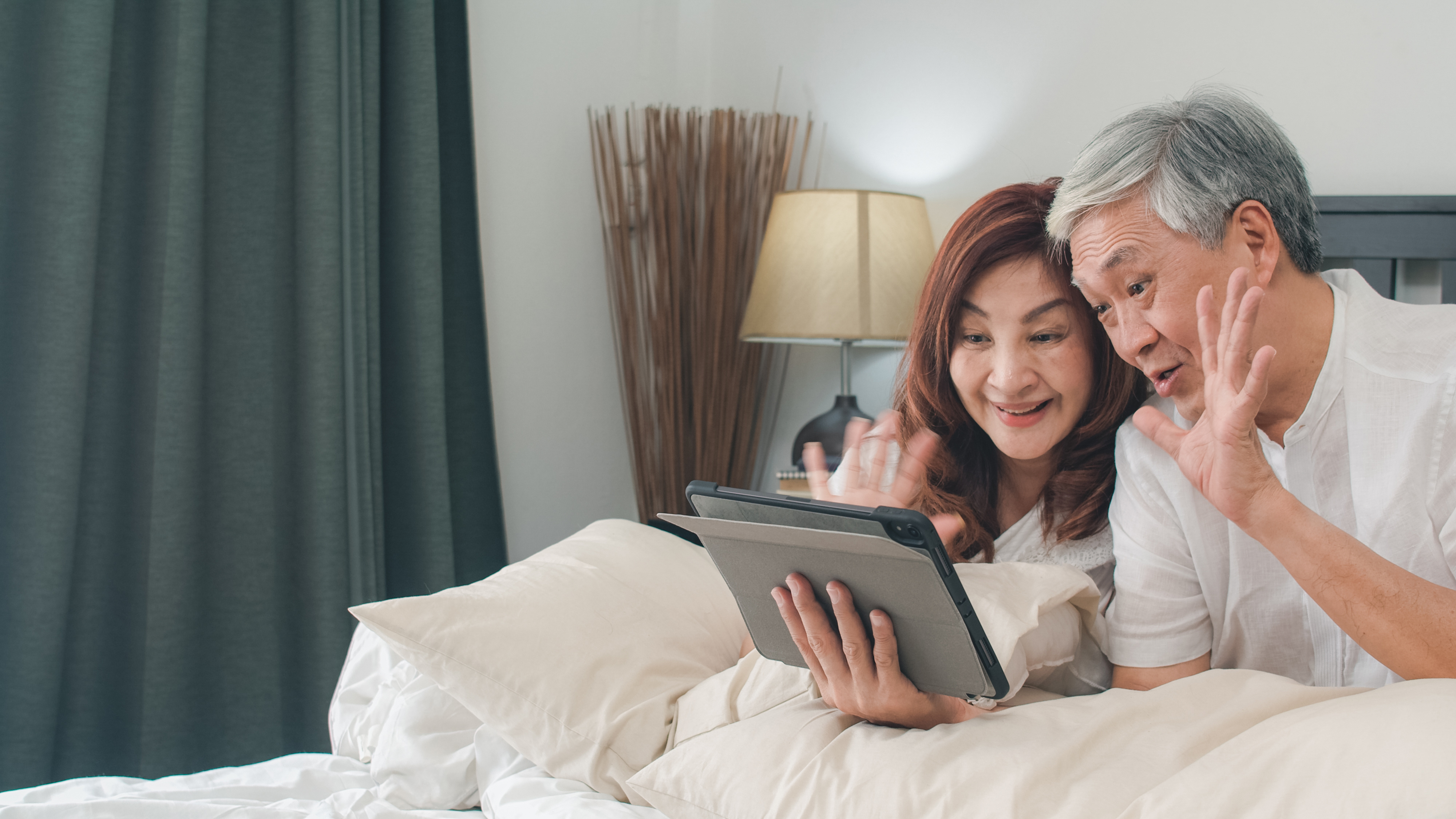 Senior couple using a tablet at home to make a web based call to grandchildren