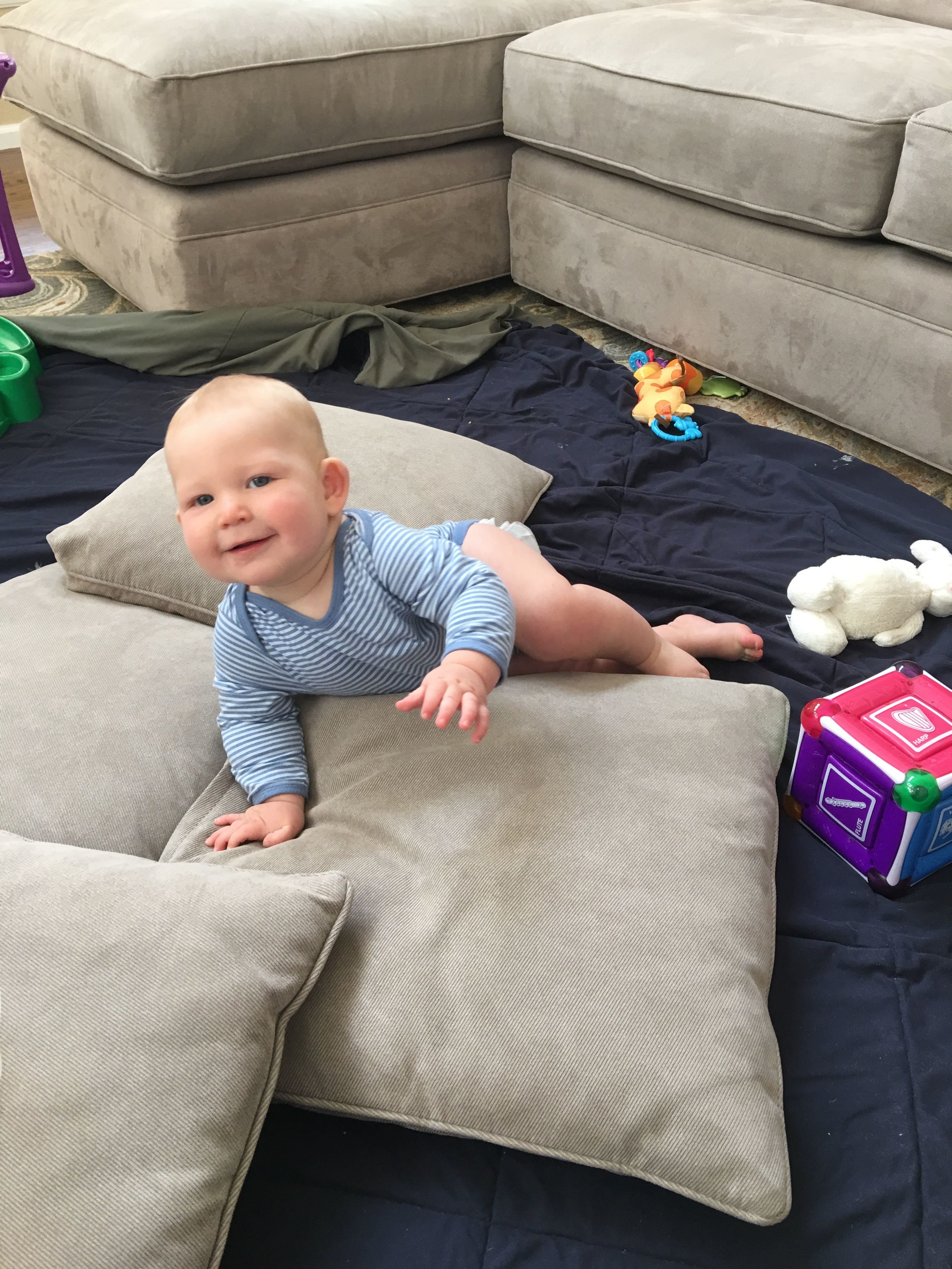 A baby crawls over cushions
