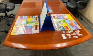 A table is laid out with board games and a barrier rests between the two players blocking their view of each other.